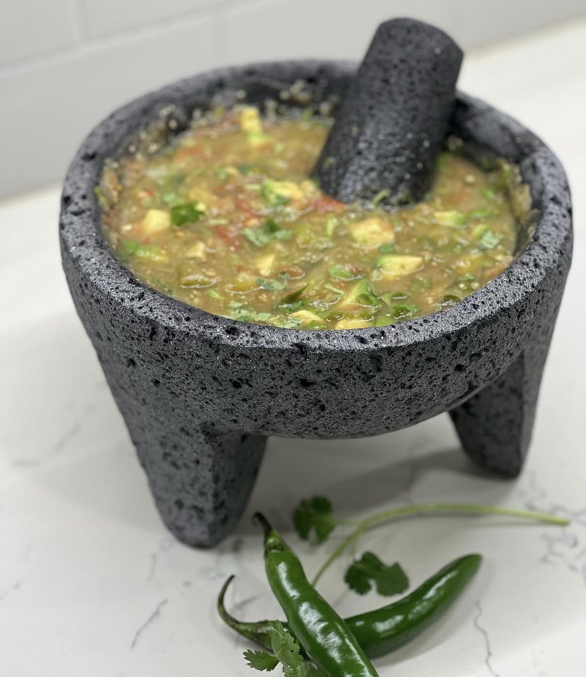 Salsa Azteca in a volcanic-stone molcajete with fresh serrano chiles and cilantro